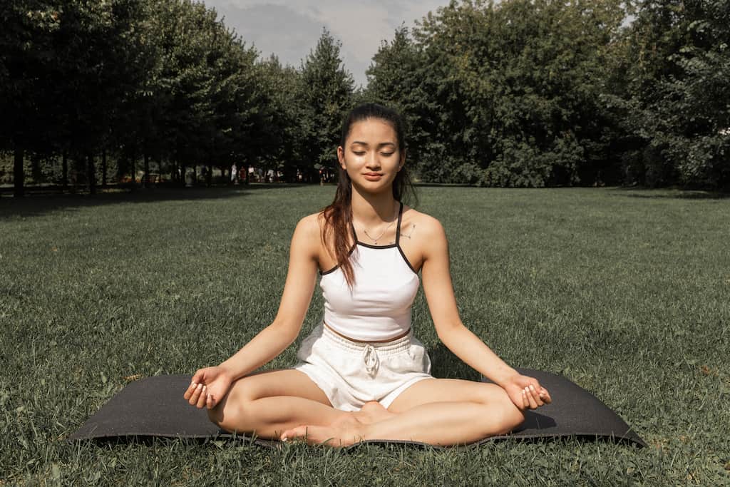 woman sitting on the grass and meditating in nature