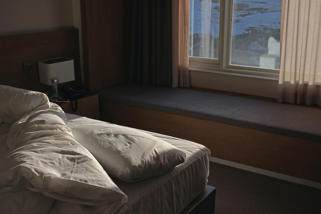 image of a bed in front of a windown in the afternoon, evoking the relaxionship between mindfulness and sleep