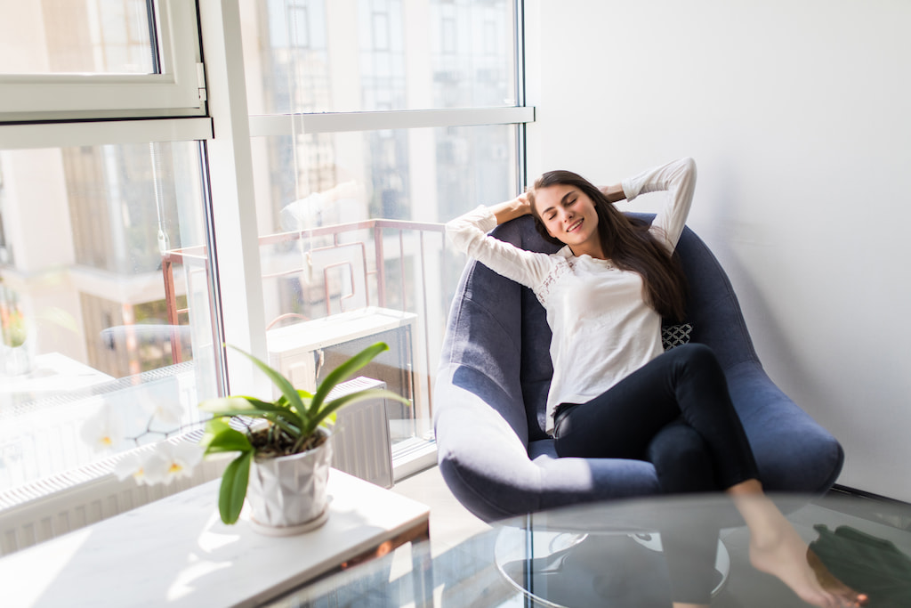 image of a person sitting on a chair, she looks relaxed and confident, evoking the feeling of getting out of the comfort zone for her wellbeing
