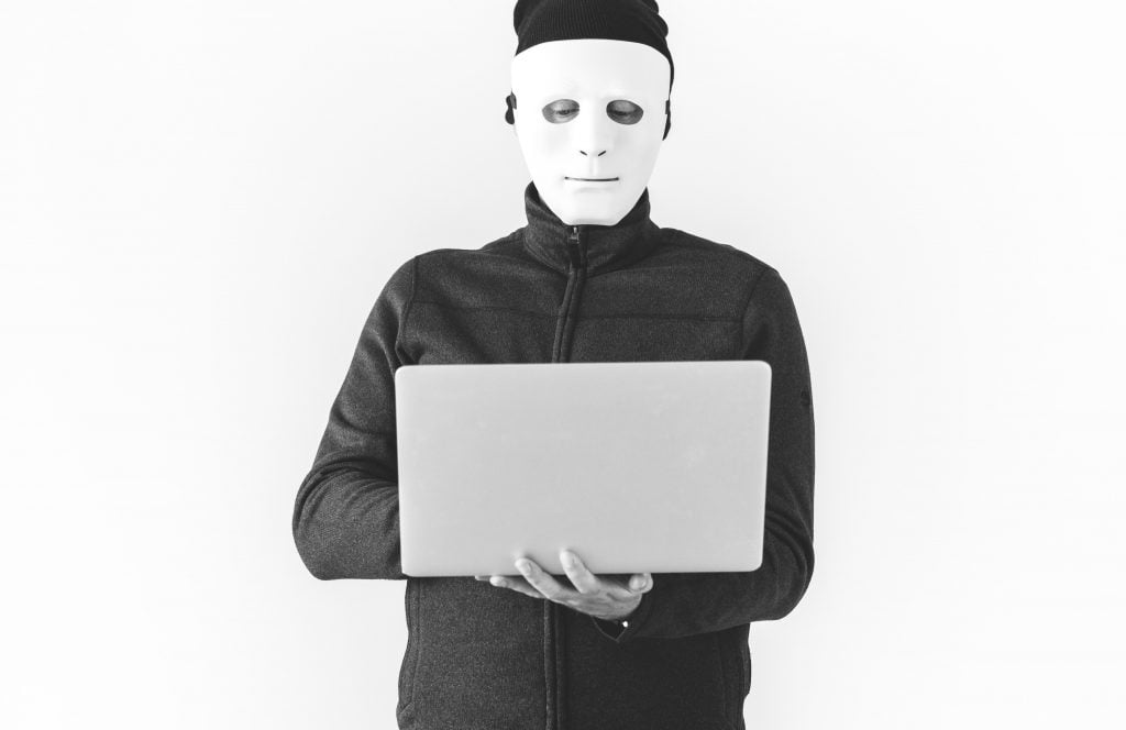 person with a mask using laptop