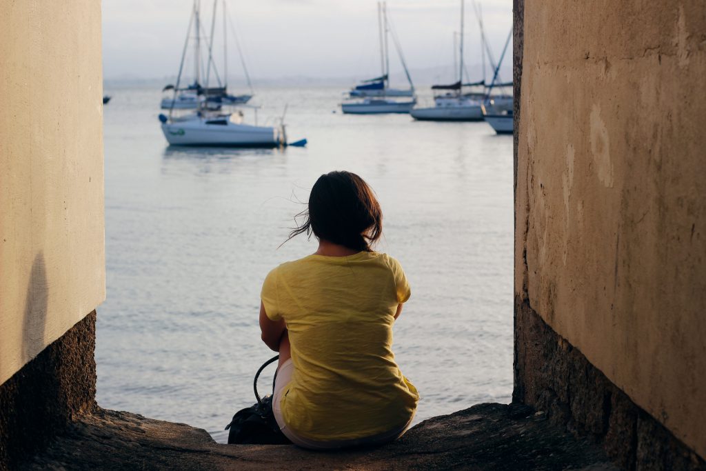 woman sitting by the water, pensive and thoughtful