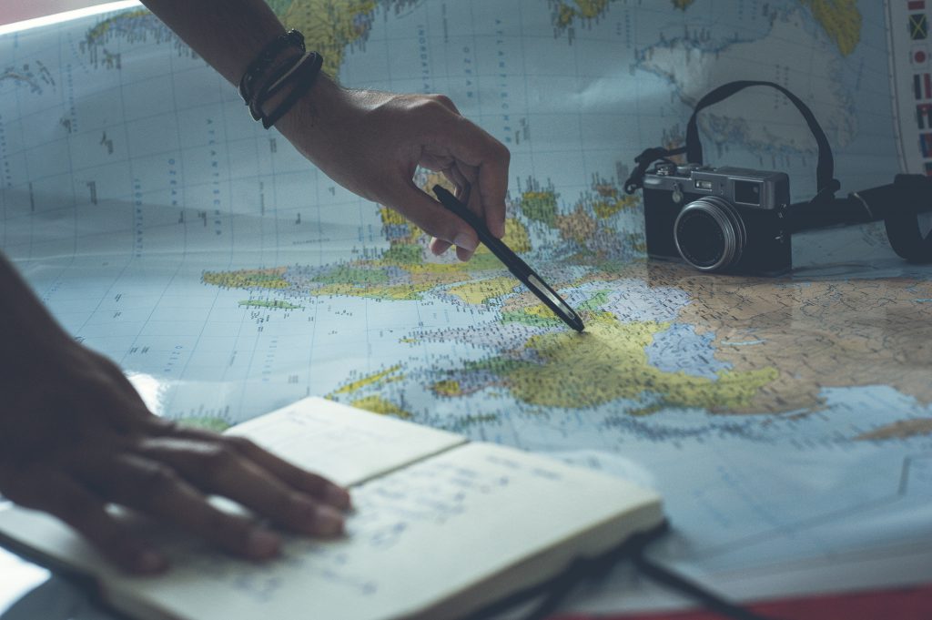 picture of someone pointing to a map with their pen planning a trip