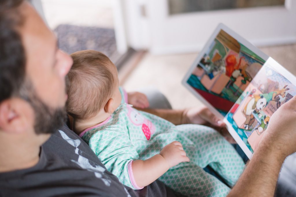 man reading book with a baby