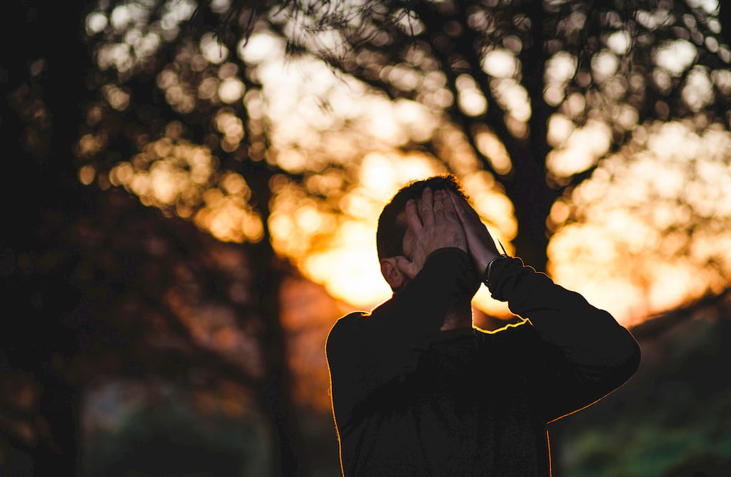 man closes his face with his hands