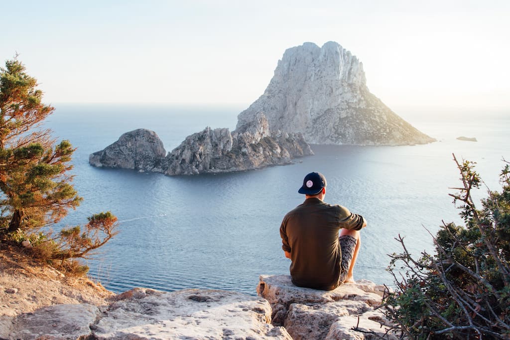 man sitting on the rocks and watching the sea