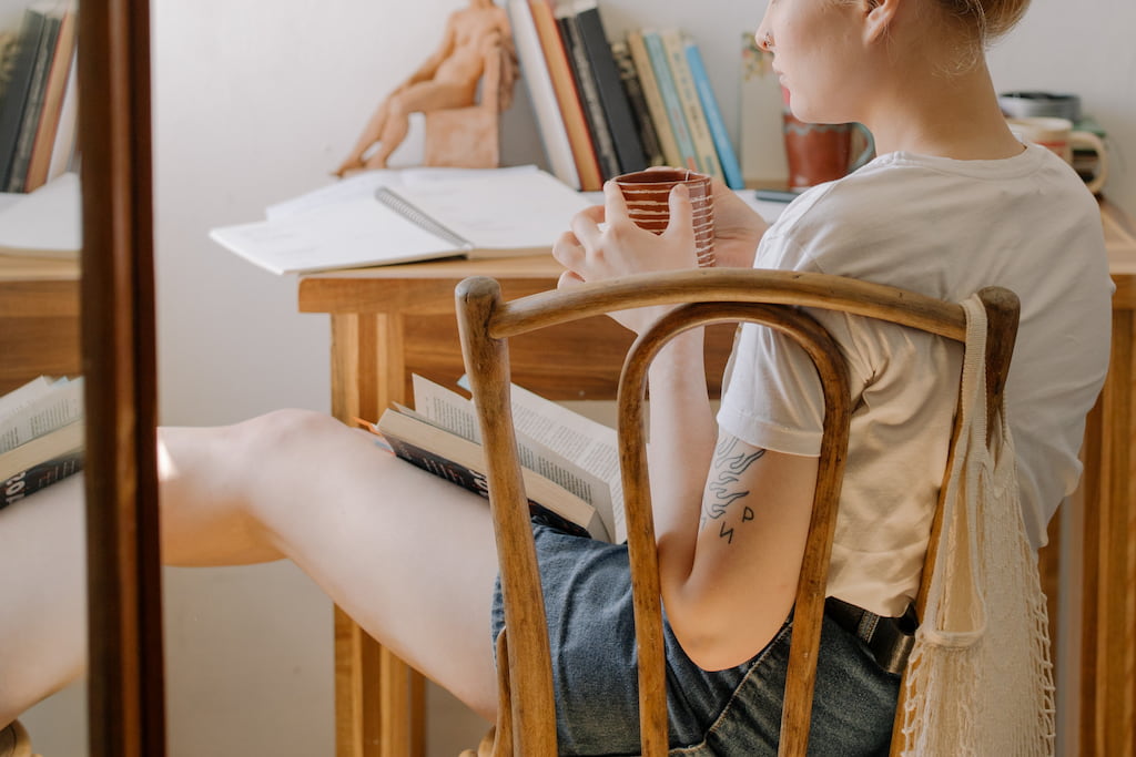 thoughtful woman sitting in her room while holding a coffee