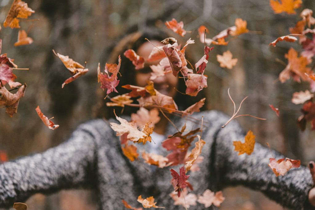 happy woman throwing autumn leaves 