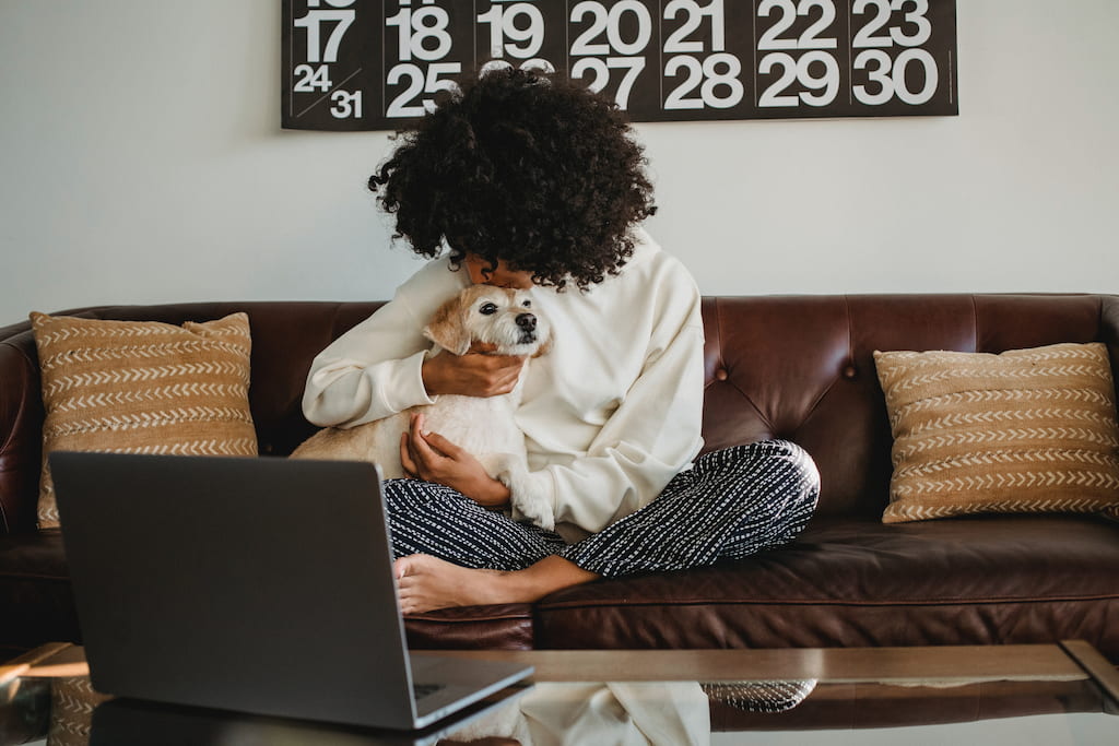 woman hugging her dog and looking at the computer