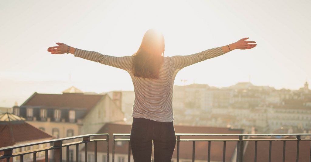 Woman standing on balcony in sunshine